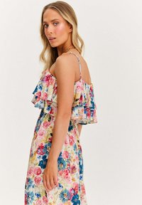 Kwiatowa sukienka maxi w kolorze różowym, niebieskim i zielonym, z warstwowymi falbanami przy dekolcie, cienkimi ramiączkami oraz zwiewną spódnicą ozdobioną różnorodnymi kwiatami.