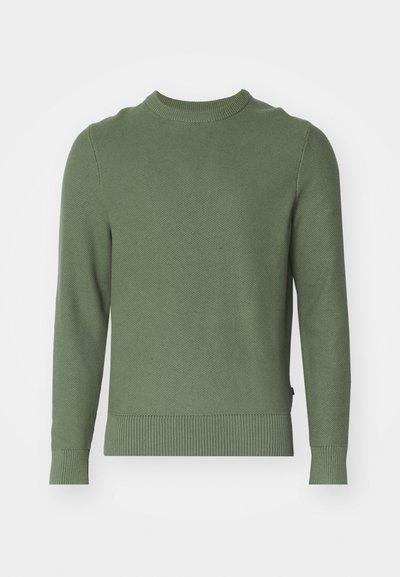Roheline kudumiga sviiter ümmarguse kaelusega, pikad varrukad, soonikkoes mansetid ja ääreosa. Omab tekstuurset pinda ja minimalistlikku disaini.