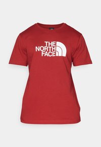 Red cotton t-shirt featuring a white logo design of "THE NORTH FACE" with curved accents. Short sleeves and crew neckline.