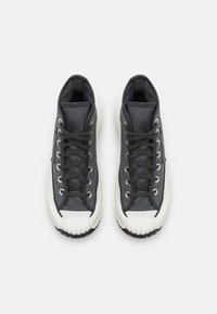 Hoge sneakers met een donkergrijze canvas bovenkant, een witte rubberen teenkap en een gemarmerde crèmekleurige tussenzool. Heeft zwarte veters en metalen ogen.