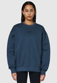 Granatowy, oversize'owy sweter wykonany z mieszanki bawełny, z okrągłym dekoltem i napisem "HALO" w kolorze czarnym, umieszczonym na klatce piersiowej.
