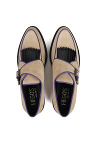 Beżowe zamszowe buty z czarną gumową podeszwą, z ozdobnym paskiem, fioletowymi akcentami, teksturowanym wykończeniem na palcach i płaskim designem.