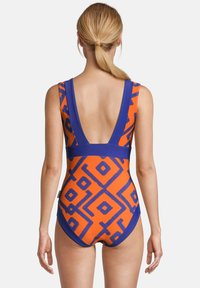 Maillot de bain une pièce avec un motif géométrique orange et bleu, doté d'un décolleté profond dans le dos et de bretelles contrastantes. Matière douce et extensible.