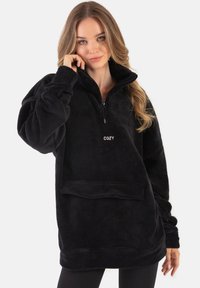 Czarny polarowy sweter z wysokim kołnierzem, na pół zamkiem błyskawicznym, z przednią kieszenią oraz haftem "COZY" na klatce piersiowej; luźny krój i miękka faktura.