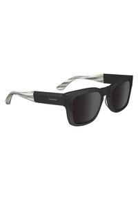 Gafas de sol negras con un bold diseño de marco cuadrado y lentes oscuros. Acentos de metal plateado en las varillas. Diseño limpio y moderno.