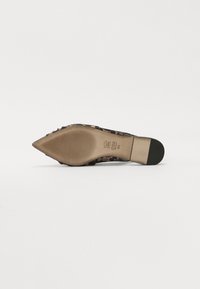 Chaussure à bout pointu avec une tige en tissu imprimé léopard, accents en tan, un talon effilé et une semelle texturée. Marquage subtil embossé au dos.