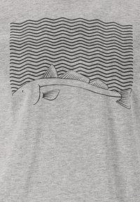 Harmaa t-paita, jossa on musta kalakuvio ja aaltoilevat viivat ylhäällä, jotka kuvastavat vettä. Yksinkertainen muotoilu ja sileä pinta.