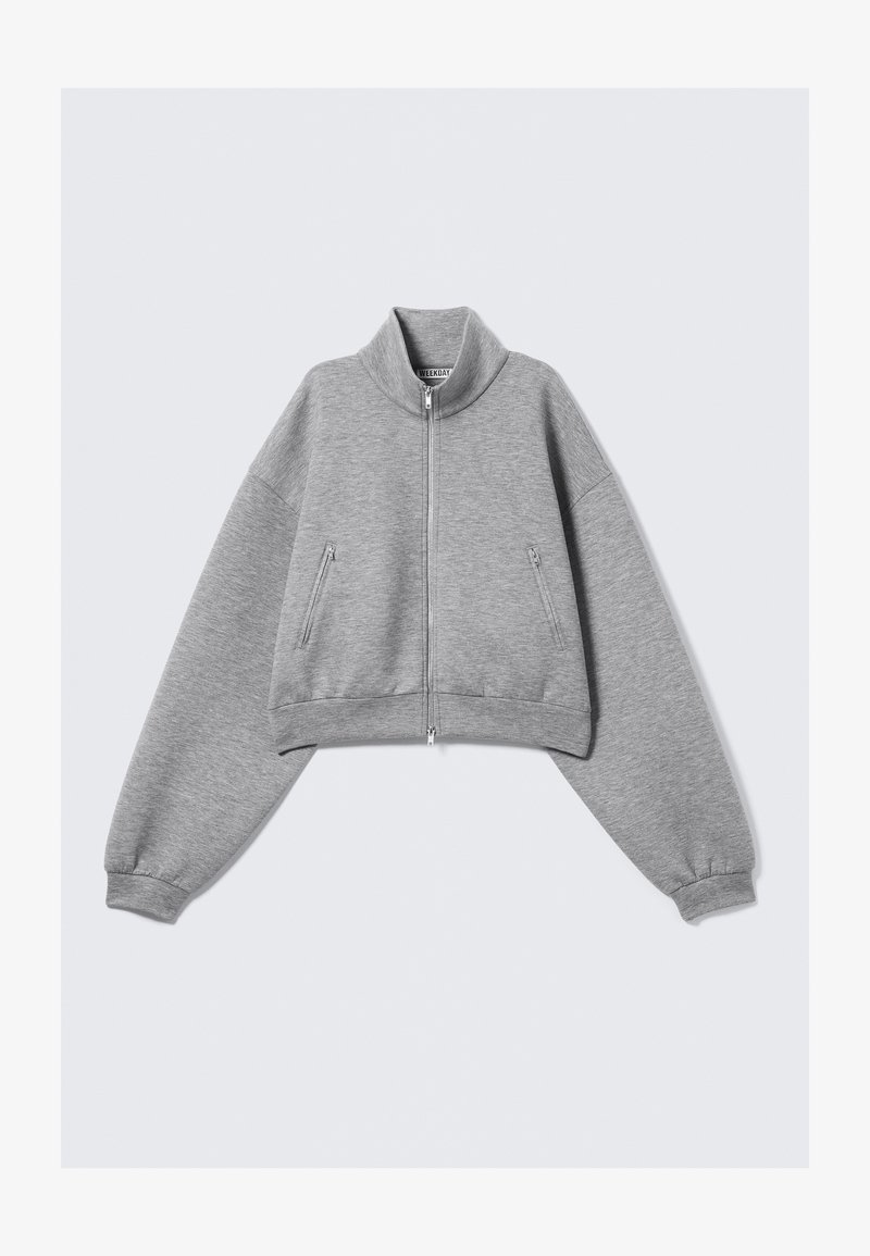 Γκρι κοντό ζακέτα με φερμουάρ, ψηλό γιακά, μακριά μανίκια και τσέπες με φερμουάρ από τη μία πλευρά, εμφανίζεται σε λευκό φόντο.