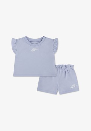 Ensemble Nike pour tout-petit violet clair avec haut à manches courtes volantées et short à taille élastique, tous deux ornés de logos Nike blancs.
