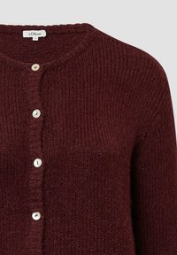 Burgunderfarbener Strickcardigan mit rundem Ausschnitt, versehen mit fünf weißen Knöpfen und einem strukturierten Muster. Das Material wirkt weich und gemütlich.