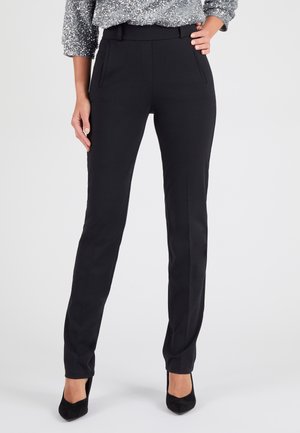 Pantaloni neri su misura con una texture liscia, dotati di tasche laterali e una vestibilità slim. Abbinati a tacchi a punta neri e un top glitterato.