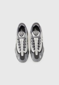 Paire de baskets New Balance 1000 grises et blanches avec lacets, vue de dessus sur un fond clair uni.