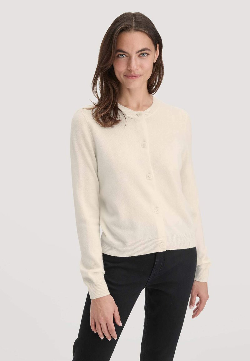 Cremfarbener Cardigan aus weichem Material, mit rundem Halsausschnitt, fünf Knöpfen auf der Vorderseite sowie geripptem Saum und Bündchen.