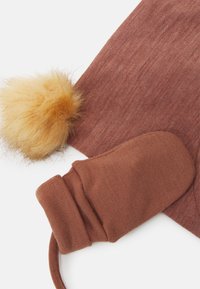 Gorro de malha castanho com um pompom amarelo fofinho; luvas sem dedos a condizer; textura suave, design simples e tons quentes.