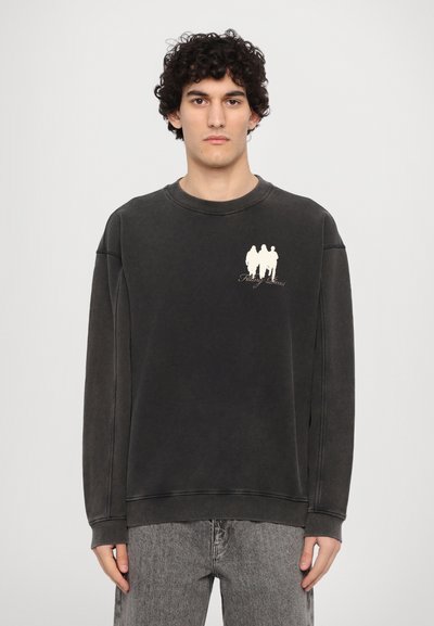 Svart oversized hettegenser med ribbestrikket krage og mansjetter. Har et lite hvitt grafisk design på brystet. Laget av myk bomull.