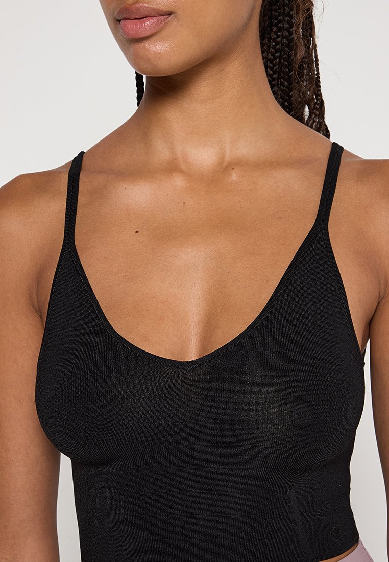 Top de tirantes finos negro con canalé y escote pronunciado, con una textura suave y una silueta ajustada.