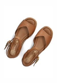 Sandali in pelle marrone con design open-toe, parte superiore a fasce incrociate e chiusura con fibbia. Fodera interna morbida e suola texturizzata.