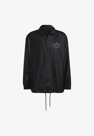 Giacca nera leggera con chiusura a bottoni, fondo con coulisse e polsini elastici. Caratterizzata da un logo ricamato blu sul petto.