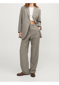Costume gris ajusté composé d'un blazer ample et de pantalons à jambes larges. Le tissu semble lisse avec un léger éclat.