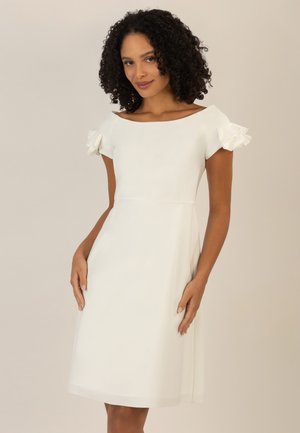 Weißes Kleid mit einem taillierten Oberteil, A-Linie Rock und schulterfreien Design. Besitzt Rüschendetails an den Ärmeln. Glatte Textur.