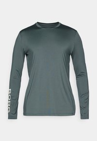 Dlhý rukáv športovej košele v tmavozelenej farbe, vyrobenej z hladkého, priedušného materiálu. Má biele písmo "BORG" na ľavom rukáve.