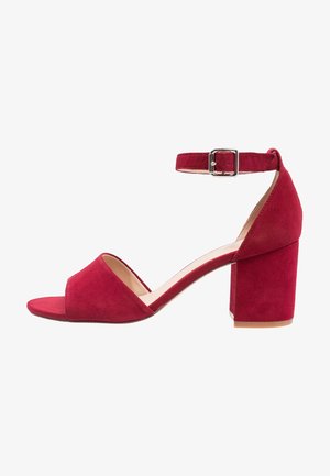 Sandale à talon en daim rouge avec bout ouvert, bride de cheville ajustable et talon épais carré. Doublure intérieure lisse et semelle plate.