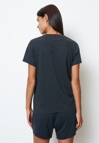 Mørkegrå kortærmet t-shirt lavet af blødt stof, med en rund halsudskæring og en afslappet pasform, parret med matchende shorts.