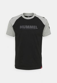 Sort kortærmet T-shirt med grå raglanærmer. Har "HUMMEL" logo i mørkegrå og en lille rød mærkat nederst. Fabrikationen er en bomuldsblanding.