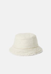 Quilted cream bucket hat with a soft textured brim and branded patch, featuring a rounded crown and relaxed fit.