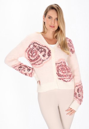 Hellrosa Strickjacke mit großen, floral gestalteten Pailletten in Dunkelrosa. Verfügt über eine Knopfleiste und gerippte Bündchen sowie Saum. Weicher, strukturierter Stoff.