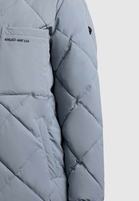 Helehall tikitud jopesärk, millel on ees tasku ja tasku kohal musta värvi tikitud tekst "KHUJO EST. 2001".