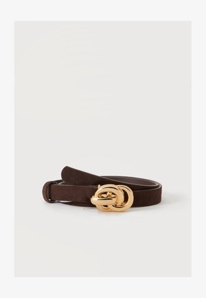 Ceinture en daim marron foncé avec une grande boucle dorée brillante entrelacée, roulée sur un fond uni clair.