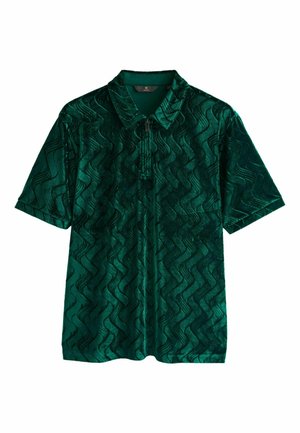 Polo verde din catifea cu un model ondulat și închidere cu fermoar în față. Mâneci scurte și un design clasic al gulerului.
