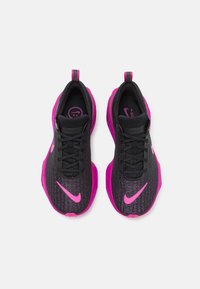 Et par sorte og lys pink Nike løbesko med strikket tekstur, pink swooshes og tykke pink såler set ovenfra på en hvid baggrund.