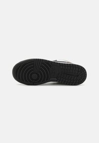 Sneaker-sulan har en texturerad svart gummi med cirkulära och linjära mönster, vilket ger grepp och hållbarhet.