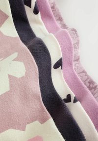 Primer plano de cinco telas de punto dobladas en rosa, morado, blanco y negro con patrones florales y de corazones.
