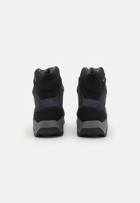 Bottes de randonnée noires avec une tige en mesh texturé, un col rembourré et une semelle en caoutchouc grise. Motif de rayures diagonales remarquable sur le côté.