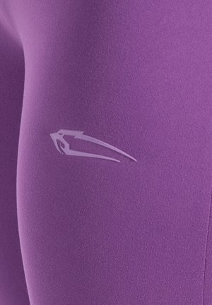 Paarse legging gemaakt van zacht, rekbaar materiaal; heeft een subtiel wit logo op de dij; gladde textuur zonder zichtbare patronen.