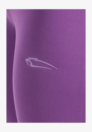 Paarse legging gemaakt van zacht, rekbaar materiaal; heeft een subtiel wit logo op de dij; gladde textuur zonder zichtbare patronen.