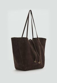 Bolso tote de ante marrón con cierre ajustable de cordón, dos asas largas y una textura suave. El diseño presenta una silueta minimalista.