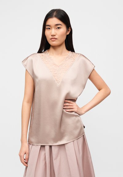 Τοπ από σατέν σε ανοιχτό μπεζ χρώμα με δαντελένιο ντεκολτέ σε σχήμα V και κοντά μανίκια. Λείο υλικό με ελάχιστες ραφές και χαλαρή εφαρμογή.