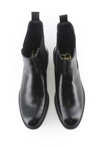 Botas de cuero negro hasta el tobillo con textura suave, paneles laterales elásticos y tiradores. Punta redondeada y detalle de costura sutil alrededor de la suela.