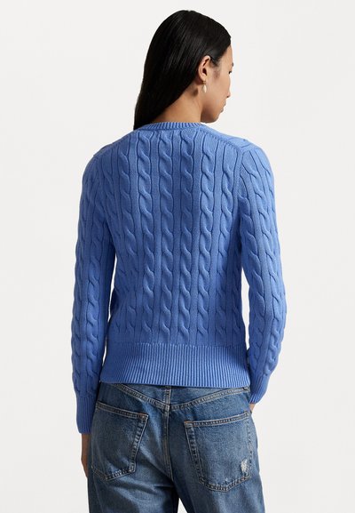 Pull en maille bleu avec un ourlet et des poignets côtelés, présentant des motifs texturés. Porté sur un jean taille haute, montrant la vue de dos.
