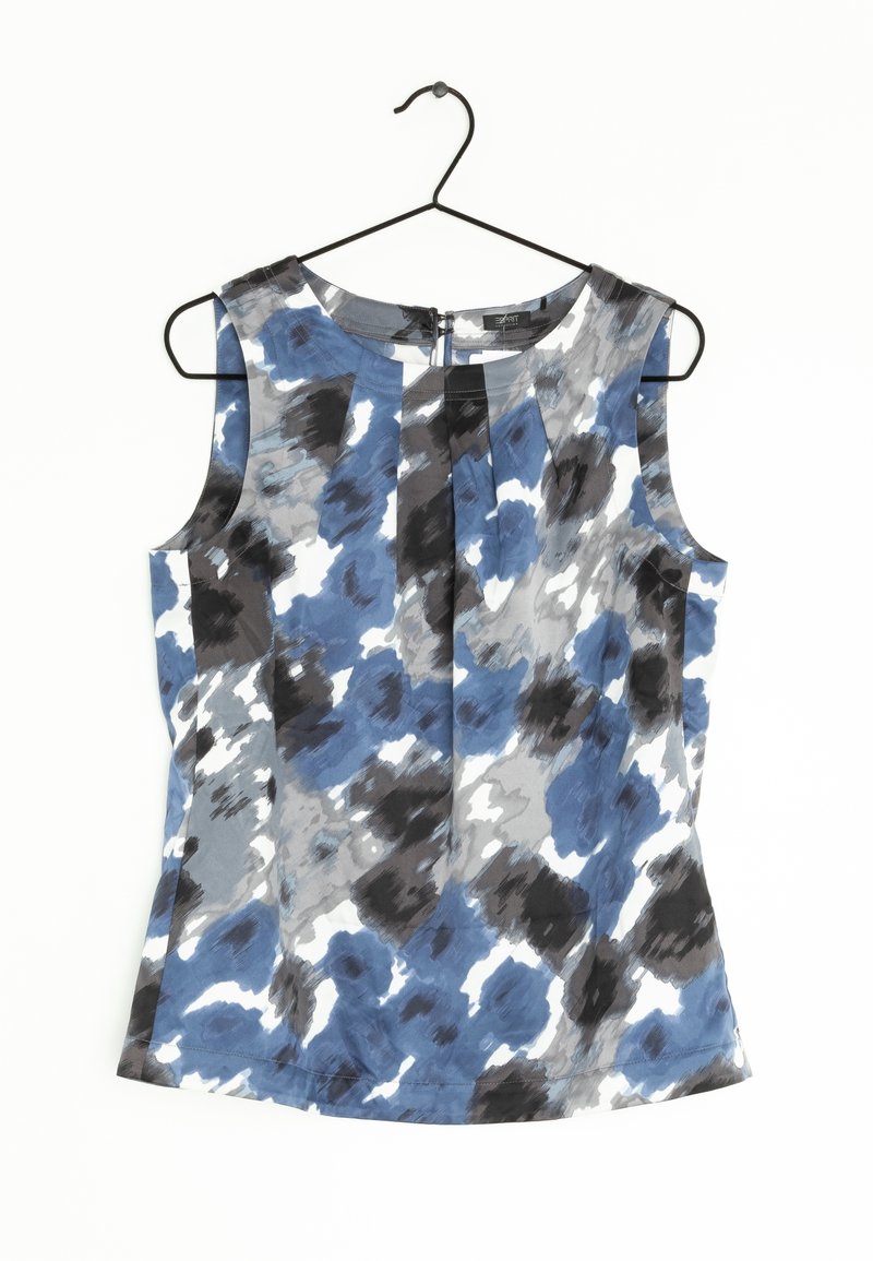 Blouse sans manches avec motif abstrait bleu, noir, gris et blanc suspendue sur un cintre noir sur fond blanc.