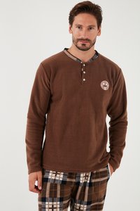Brun fleece langærmet skjorte med knaplukning og krave. Ternet mønster ved halsudskæringen. Båret med ternede pyjamasbukser i brune nuancer.