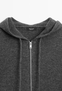 Grey zip-up hoodie made of knit fabric, featuring a cozy hood, silver zipper, and label reading "Massimo Dutti" inside the collar.