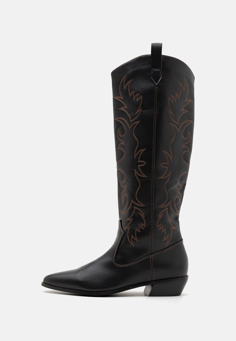 Bota de couro preta até ao joelho com bico afinado, realces de costura castanha e bordado decorativo em padrão de folhas ao longo do cano. Salto grosso.