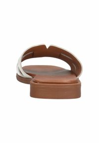 Flat sandals with a brown sole, light beige straps, and a cut-out design. The footbed is smooth, and the straps have a textured finish.
