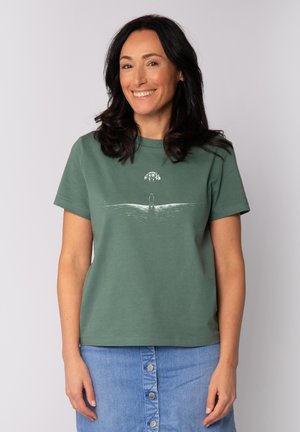 Groene katoenen t-shirt met korte mouwen en ronde halslijn, met een witte grafische illustratie van een figuur en een boom.