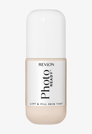 Flacon de Revlon PhotoReady Lift & Fill Skin Tint avec un capuchon blanc et un fond de teint liquide beige visible à l'intérieur.